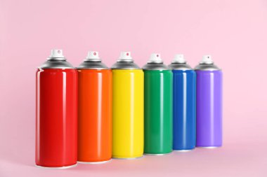 Pembe arka planda renkli sprey boya kutuları
