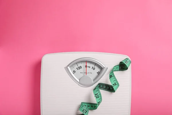 Weight loss concept. Scales and measuring tape on pink background, top view. Space for text