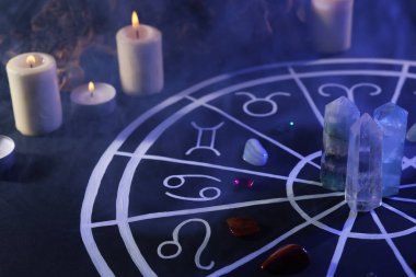 Zodyak işaretleri için doğal taşlar, astroloji çizelgesi ve siyah masada yanan mumlar. Renk tonu etkisi