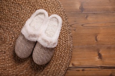 Ahşap zeminde bir çift sıcak terlik ve hasır döşeme, düz yatış. Metin için boşluk