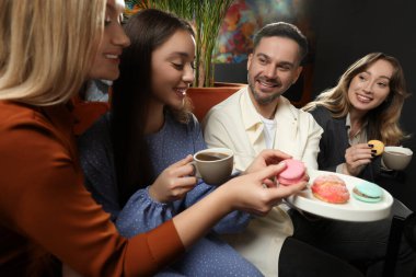 People with coffee and macarons spending time together in cafe