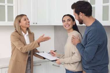 Emlakçı ve çift yeni dairede sözleşme imzalıyorlar.