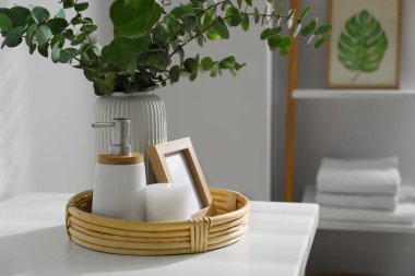 Vase with eucalyptus branches and toiletries in bathroom, space for text. Interior design