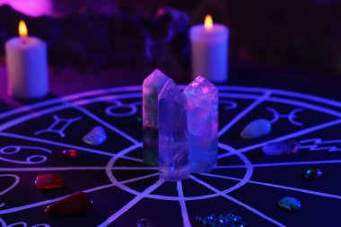 Zodyak işaretleri için doğal taşlar, astroloji çizelgesi ve siyah masada yanan mumlar. Renk tonu etkisi