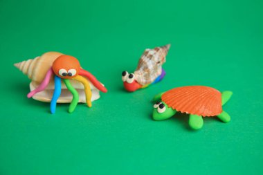 Kaplumbağa, yengeç ve salyangoz yeşil arka planda plastikten yapılır. Çocukların el yapımı fikirleri.