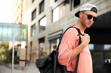 Şık güneş gözlüklü ve sırt çantalı yakışıklı genç adam.