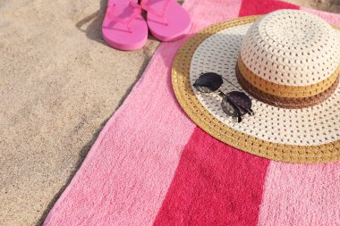 Beach towel with slippers, straw hat and sunglasses on sand