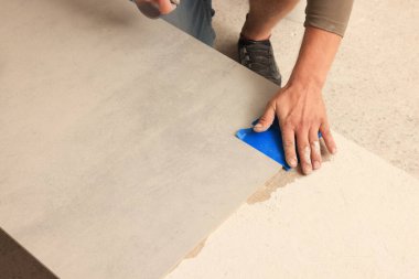 Worker preparing tile for installation indoors, closeup