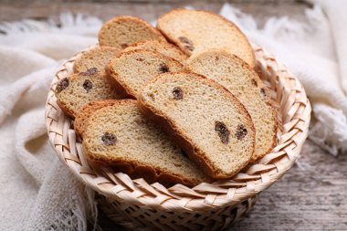Sweet hard chuck crackers with raisins in wicker basket on wooden table, closeup