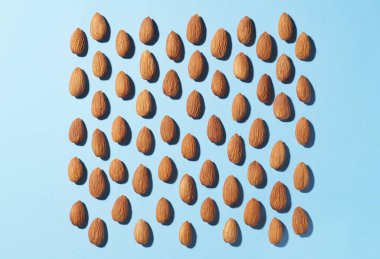Delicious raw almonds on light blue background, flat lay