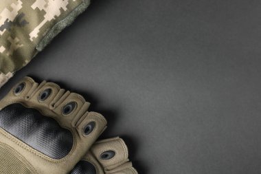 Tactical gloves and uniform on black background, flat lay with space for text. Military training equipment