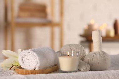 Spa composition with burning candle and herbal bags on massage table in wellness center