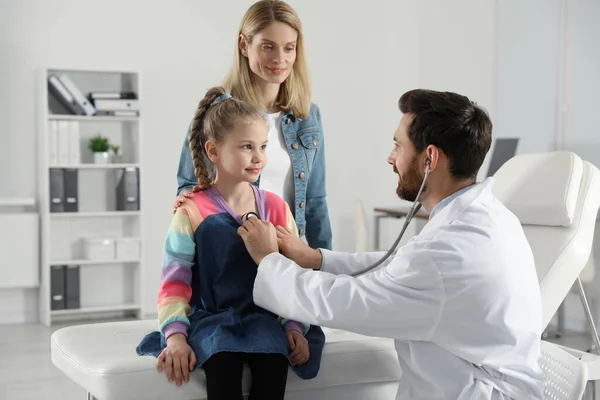 Mother and daughter having appointment with doctor. Pediatrician examining patient with stethoscope in clinic