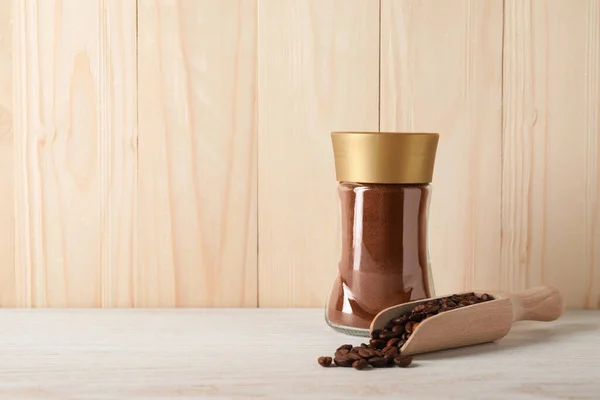 Jar and scoop with different types of coffee on white wooden table. Space for text