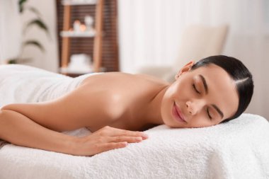 Genç bir kadın masaj salonundaki masaj koltuğunda dinleniyor.