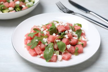 Delicious salad with watermelon, cucumber, arugula and feta cheese on white wooden table