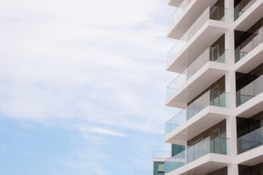 Mavi gökyüzüne karşı balkonları olan, alçak açılı bir bina. Metin için boşluk
