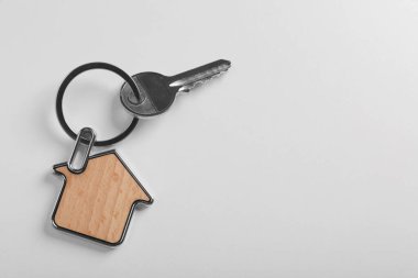 Beyaz arka planda ev şeklinde ıvır zıvırlı anahtar, üst görünüm ve metin için boşluk. Emlakçılık hizmetleri