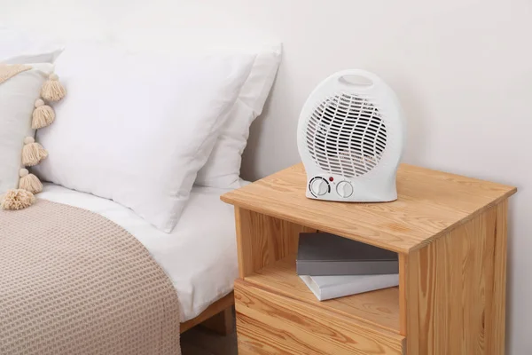 Modern electric fan heater on bedside table indoors