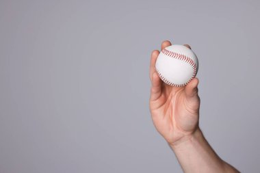 Man with baseball ball on light grey background, closeup. Space for text