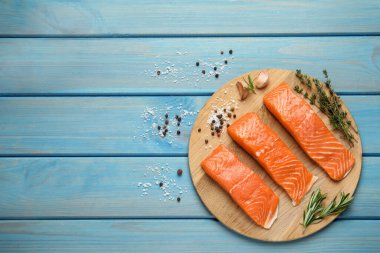 Fresh raw salmon and ingredients for marinade on light blue wooden table, flat lay. Space for text