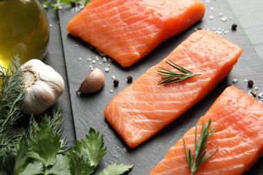 Fresh raw salmon and ingredients for marinade on black table