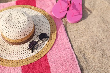 Beach towel with slippers, straw hat and sunglasses on sand