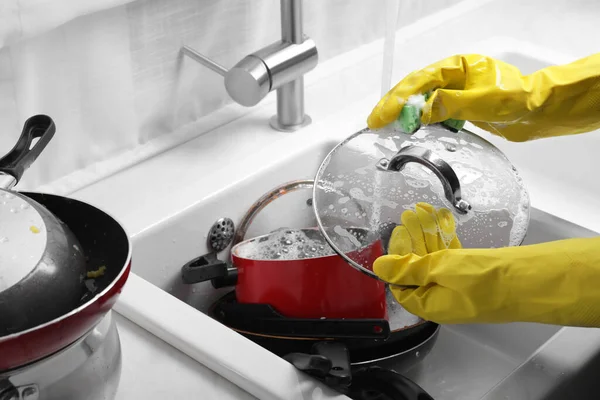 Woman washing glass lid in kitchen sink, closeup
