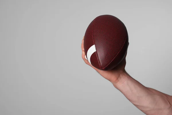 Man with American football ball on light grey background, closeup. Space for text