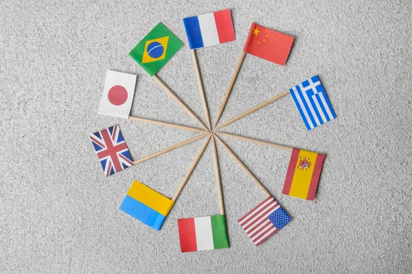 stock image Many small paper flags of different countries on grey textured table, flat lay
