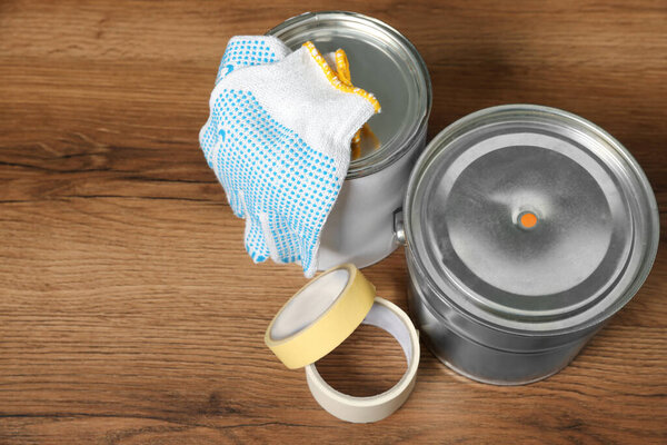 Банки с оранжевой краской и ремонтным оборудованием на деревянном столе, вид сверху. Пространство для текста