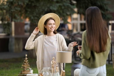 Women shopping on garage sale near table with different items in yard