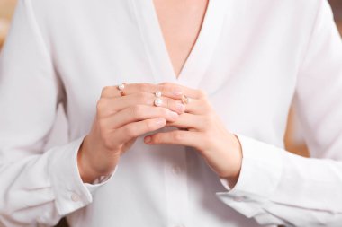 Young woman trying on elegant rings with pearls indoors, closeup