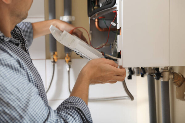 Man opening top of gas boiler indoors, closeup