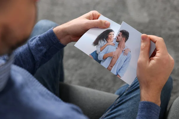 Man ripping photo on sofa indoors, closeup. Divorce concept