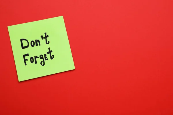 Paper note with phrase Don\'t Forget on red background, top view. Space for text