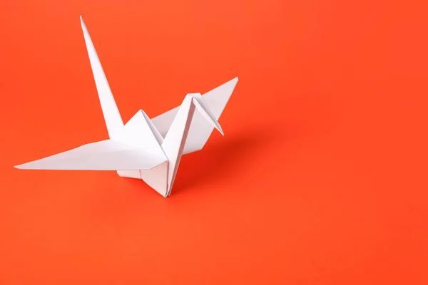 Origami art. Handmade paper crane on orange background, space for text