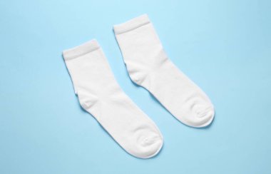 Açık mavi arka planda bir çift beyaz çorap.