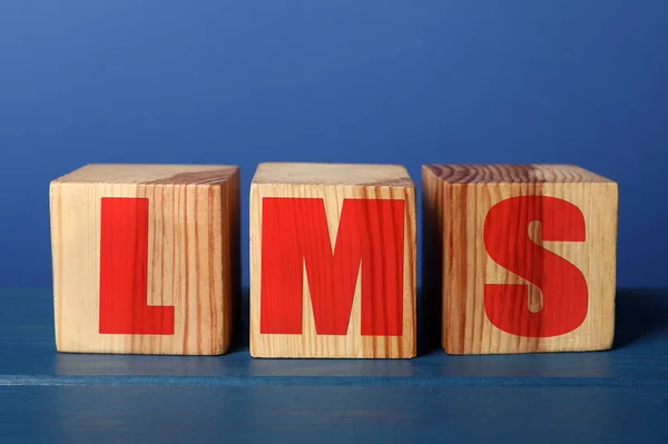 Learning management system. Cubes with abbreviation LMS on blue wooden table