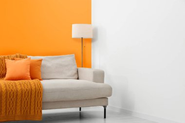 Stylish room with cosy sofa near orange wall. Interior design