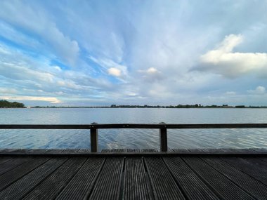 Nehir ahşap iskele ve bulutlu gökyüzü manzarası