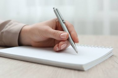 Ahşap masada deftere yazan kadın, yakın plan.