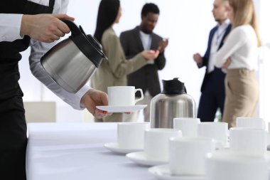 Garson kahve molası sırasında sıcak içecek dolduruyor.