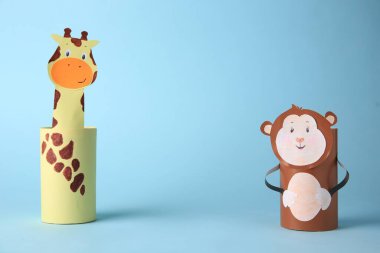 Toy monkey and giraffe made from toilet paper hubs on light blue background, space for text. Children's handmade ideas