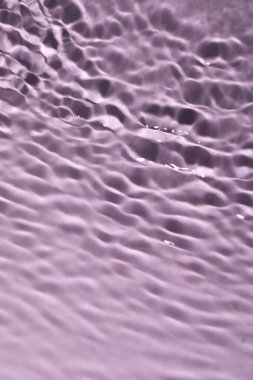 Menekşe arkaplanda dalgalı yüzeyi olan suyun yakın görüntüsü