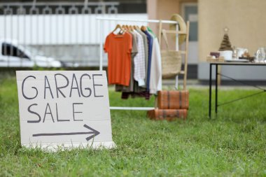 Sign Garage sale written on cardboard in yard