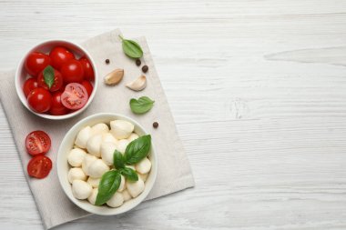 Lezzetli mozzarella topları kasede, domates ve sarımsak beyaz ahşap masada, düz yerde. Metin için boşluk