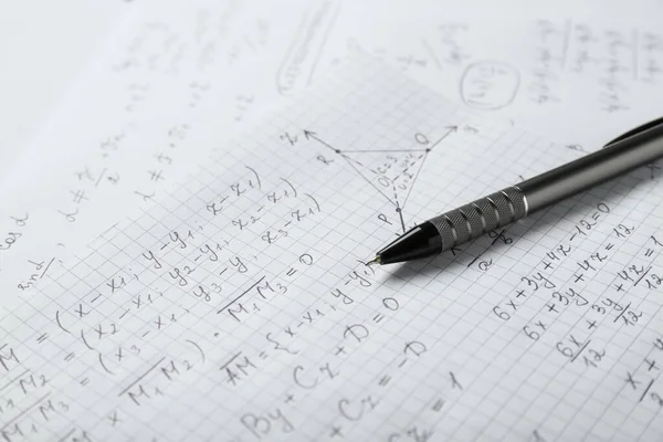 Sheets of paper with different mathematical formulas and pen, closeup
