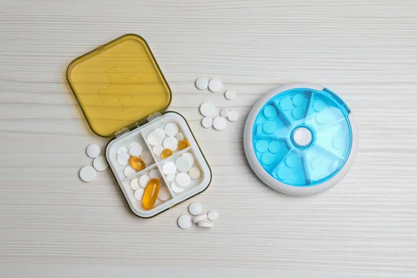 Pill boxes with medicaments on white wooden table, flat lay
