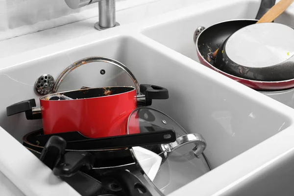 Messy pile of dirty kitchenware in sink